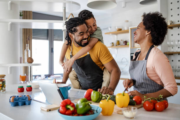 Couple with their son are in the kitchen and they are having fun while preparing lunch