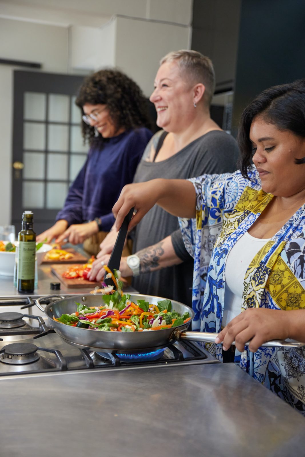 three women prepping and cooking a meal together