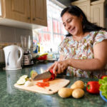 Couple with their son are in the kitchen and they are having fun while preparing lunch